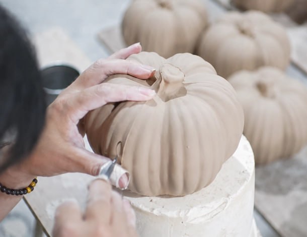 Artisan at the bench hand-carving and refining ceramic pumpkins